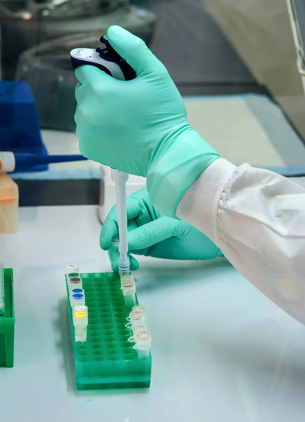 A laboratory worker using a pipette with gloved hands