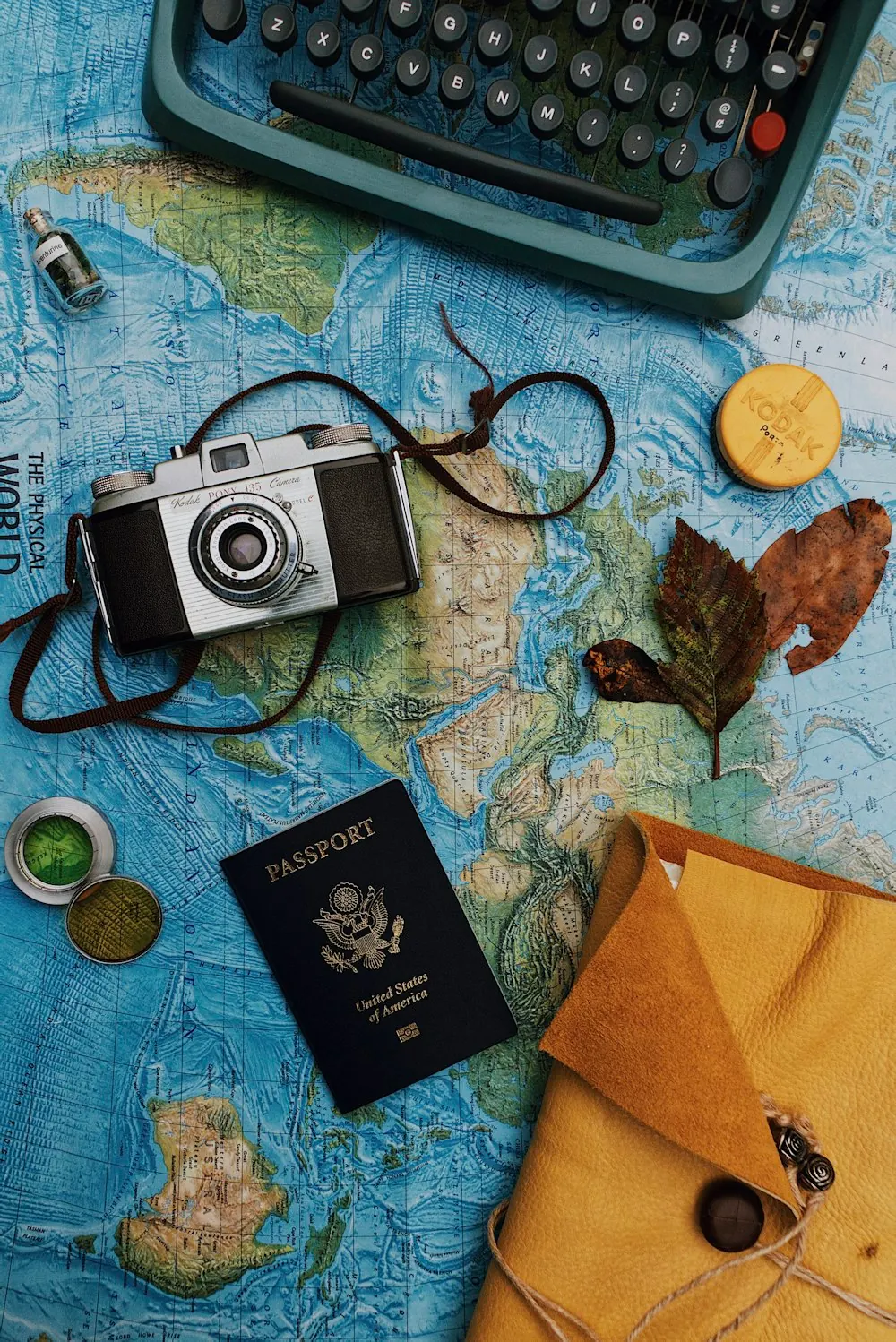 Travel map, passport cover and camera arranged on a table